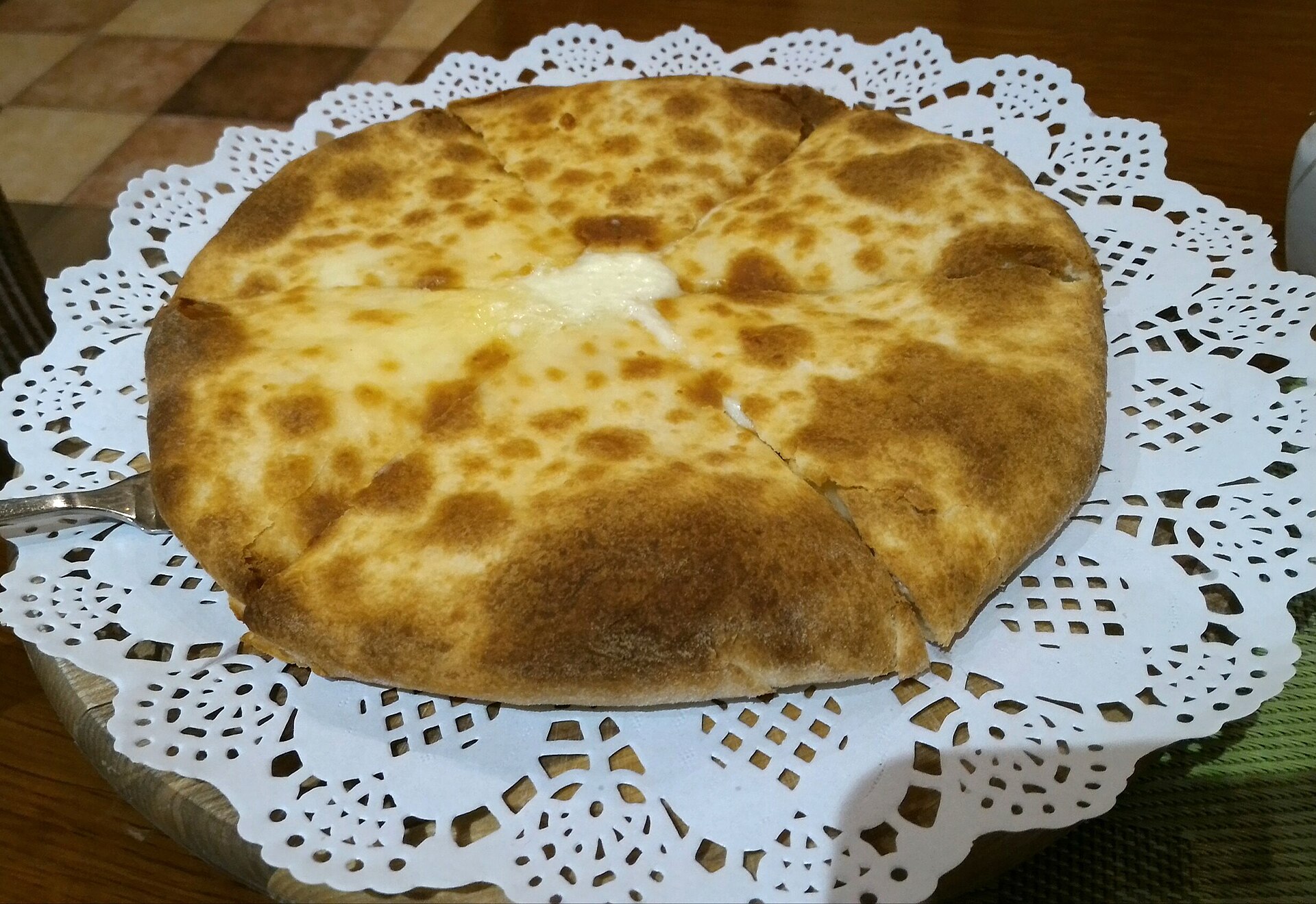 Round Imeretian cheese bread cut into wedges on a plate
