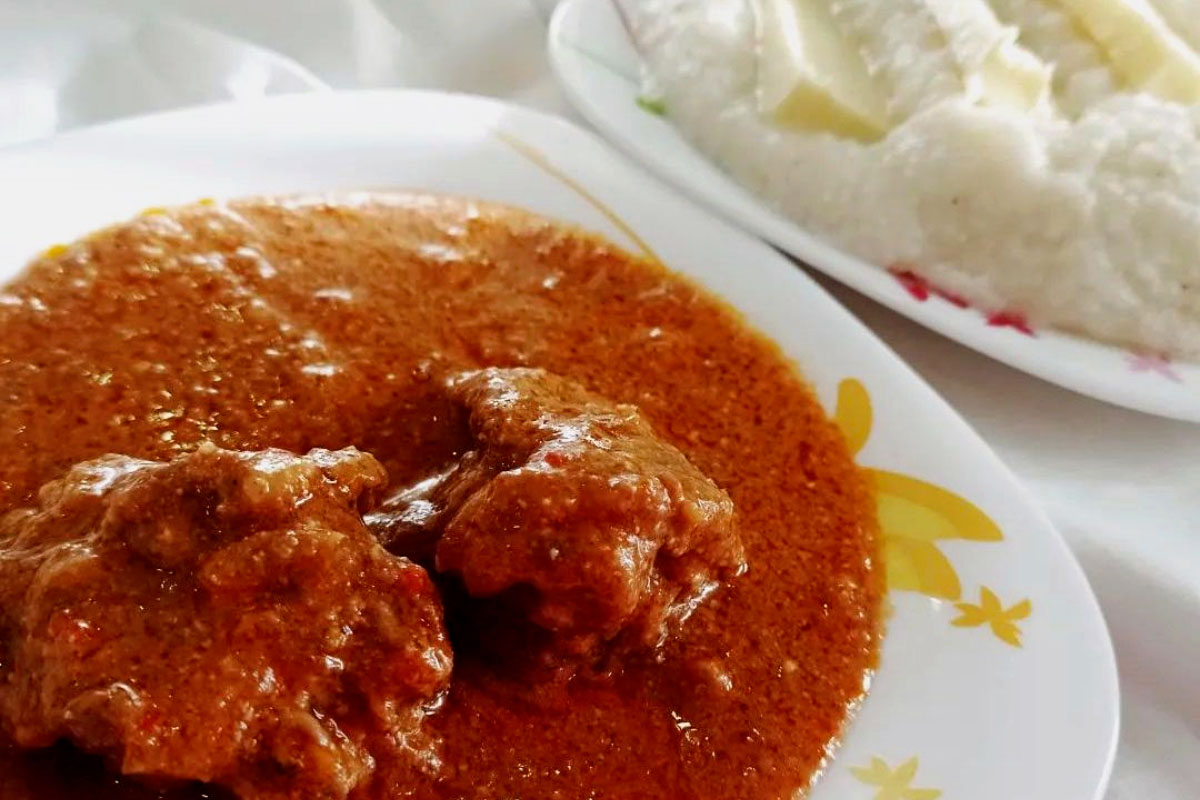 Rich meat kharcho served beside white ghomi cornmeal