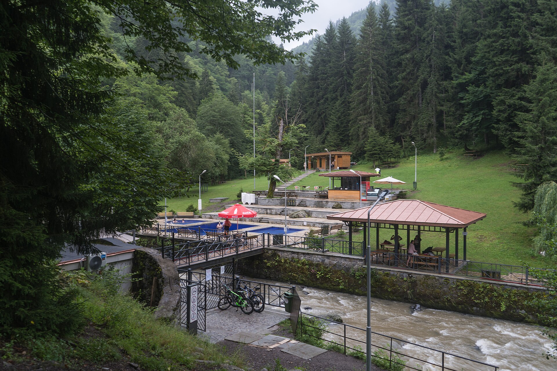 Outdoor sulfur pools beside a stream and forest near Borjomi